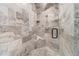 Luxurious walk-in shower featuring dual shower heads, marble tiling, and a convenient built-in seat at 6219 Woodlake Dr, Buford, GA 30518