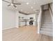 Open-concept living space featuring light floors, staircase, ceiling fan and adjacent kitchen with white cabinets at 88 Black Gum Ln # 43, Auburn, GA 30011