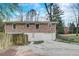 Rear view of brick home with a drive-under garage, yard, and mature trees at 3159 Nursery Se Rd, Smyrna, GA 30082