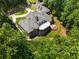 This aerial view features the brick home's backyard with terrace, mature landscaping, three car garage, and circular driveway at 1655 Arrowhead Ne Trl, Atlanta, GA 30345
