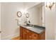 Stylish half bathroom with granite countertop, framed mirror, decorative sconces, and wood cabinets at 1655 Arrowhead Ne Trl, Atlanta, GA 30345