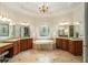 Luxurious bathroom featuring dual vanities, a soaking tub, stained glass window, and elegant lighting at 1655 Arrowhead Ne Trl, Atlanta, GA 30345