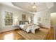 Light filled main bedroom featuring a tray ceiling, neutral tones, hardwood floors, and ensuite access at 1655 Arrowhead Ne Trl, Atlanta, GA 30345