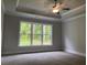 Main bedroom featuring a tray ceiling with a ceiling fan and a large window with wooded views at 1114 Low Water Crossing, Acworth, GA 30101