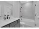 Bathroom featuring gray cabinetry, quartz countertop, white tiled walls, and tub at 6670 Benchwood Path, Cumming, GA 30028
