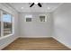 Sunlit bedroom with hardwood floors, modern tray ceiling, and large windows offering neighborhood views at 6670 Benchwood Path, Cumming, GA 30028