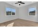 Bedroom with a modern ceiling fan, two windows, and light-colored flooring at 6670 Benchwood Path, Cumming, GA 30028