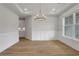 Open dining room with elegant chandelier, hardwood floors, wainscoting, and view into the kitchen at 6670 Benchwood Path, Cumming, GA 30028