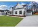 Beautiful white brick home with black trim, well-manicured lawn and attached garage on a sunny day at 6670 Benchwood Path, Cumming, GA 30028
