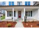 Close-up of a front porch featuring a red door, white columns, and manicured landscaping at 6670 Benchwood Path, Cumming, GA 30028