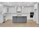 Open kitchen featuring an island, white cabinets, stainless steel appliances, and modern pendant lights at 6670 Benchwood Path, Cumming, GA 30028