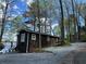 Exterior of a cozy home with dark siding, trees, lake, and a gravel area with patio furniture at 7 Yachting Way, Acworth, GA 30102