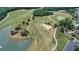 Aerial view of the lush green golf course with trees, sand traps, and a lake in the Windermere community at 6133 Malloway Ct, Cumming, GA 30041