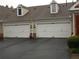 A two car garage with white doors and adjacent to well-maintained landscaping at 6133 Malloway Ct, Cumming, GA 30041