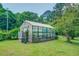A greenhouse sits on a sprawling, well-maintained yard with lush green plants and trees at 500 Cochran Rd, Covington, GA 30014