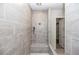 An open walk-in shower featuring light gray tile and a hand-held shower head at 498 Pearl St, Cumming, GA 30040