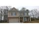 Two-story home featuring a brick-and-siding facade, a two-car garage, and a welcoming front porch with supporting columns at 6035 Spring Way, Stonecrest, GA 30038