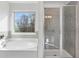Bright bathroom with soaking tub under a window and a glass-enclosed tiled shower at 6045 Spring Way, Stonecrest, GA 30038