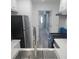 Modern kitchen with stainless steel appliances, white countertops, and wood-look flooring, leading into hallway at 1041 Kennesborough Nw Rd, Kennesaw, GA 30144