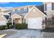 Tan two-story home with white garage doors and landscaping at 4010 Village Run Dr, Mcdonough, GA 30252