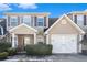 Tan two-story home with white garage door and landscaping at 4010 Village Run Dr, Mcdonough, GA 30252
