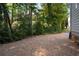 Gravel area next to the home featuring mature trees and lush shrubbery at 2493 Oldfield Nw Rd, Atlanta, GA 30327