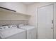 Bright laundry room, washer, dryer, and shelving at 158 Ashwood Ct, Riverdale, GA 30274