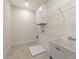 Well-lit laundry room with gray tile flooring, a large utility sink and convenient overhead storage at 4455 Ryker Rd, Cumming, GA 30041