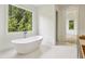 Bathroom with a freestanding tub, white tile flooring, and a large window at 825 Kenry Ct, Atlanta, GA 30342
