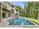 A backyard view of a modern house with a sparkling pool surrounded by well-maintained landscaping and natural greenery at 825 Kenry Ct, Atlanta, GA 30342