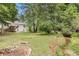 Expansive back yard with mature trees, home, deck, patio, and a peaceful creek running through the property at 104 Streambank Ct, Temple, GA 30179