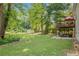Expansive backyard with mature trees, deck with patio furniture, shed and lush lawn, offering ample outdoor space at 104 Streambank Ct, Temple, GA 30179