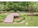 Picturesque backyard with a wooden walkway, manicured lawn, and natural foliage creating a serene retreat at 104 Streambank Ct, Temple, GA 30179