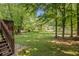 Spacious backyard with mature trees, lush lawn, and patio stairs, creating a serene outdoor retreat at 104 Streambank Ct, Temple, GA 30179