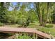Lush backyard with a charming bridge over a stream, surrounded by mature trees and greenery at 104 Streambank Ct, Temple, GA 30179