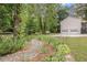 Home exterior with a decorative stream and lush landscaping leading to wooded lot and two-car garage at 104 Streambank Ct, Temple, GA 30179