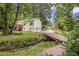 Charming home exterior with a bridge leading to a spacious, wooded lot and two-car garage at 104 Streambank Ct, Temple, GA 30179