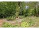 Lush landscaping featuring rocks and plants, leading to a wooded area; creating a serene and inviting outdoor space at 104 Streambank Ct, Temple, GA 30179
