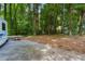 Spacious backyard area showcasing mature trees, gravel space, and additional space for parking at 978 W Mill Bnd, Kennesaw, GA 30152