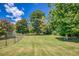 Beautiful backyard with an expansive lawn surrounded by mature trees and a classic chain link fence at 3700 Tom Brewer Rd, Loganville, GA 30052