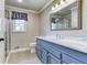 Well-lit bathroom with a blue vanity, marble countertop, and tiled floors at 3700 Tom Brewer Rd, Loganville, GA 30052