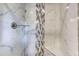 Close up of walk-in shower featuring white marble-patterned tiles and glass shelves at 3700 Tom Brewer Rd, Loganville, GA 30052