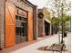 Exterior view of street front stores with brick facade, large wood doors, and sidewalk seating at 505 Godfrey Dr, Cumming, GA 30040