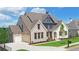 Two story home with light brick exterior, three-car garage, and landscaped yard at 5693 Brendlynn Dr, Suwanee, GA 30024