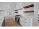 Upscale kitchen with white cabinets, marble countertops, and floating shelves at 5693 Brendlynn Dr, Suwanee, GA 30024