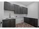 Bright laundry room, featuring dark gray cabinetry, herringbone floor, and a utility sink at 5693 Brendlynn Dr, Suwanee, GA 30024
