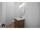 Modern powder room with a wood vanity, marble countertop, and a round mirror at 5693 Brendlynn Dr, Suwanee, GA 30024