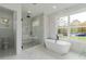Bright bathroom features soaking tub, glass shower, marble accents, and a large window at 2861 Tree Top Rd, Dacula, GA 30019
