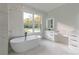 Bright bathroom features a freestanding tub with floor-to-ceiling marble and double sink vanity at 2861 Tree Top Rd, Dacula, GA 30019