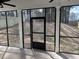 This screened porch features black trim windows and door, and a view of the backyard at 1641 Lacebark Elm Way, Lawrenceville, GA 30045